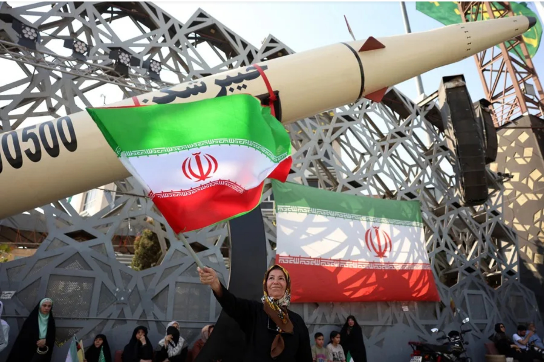 Una mujer iraní ondea una bandera nacional junto a una réplica de un misil balístico durante una manifestación en Teherán, en una imagen de archivo.